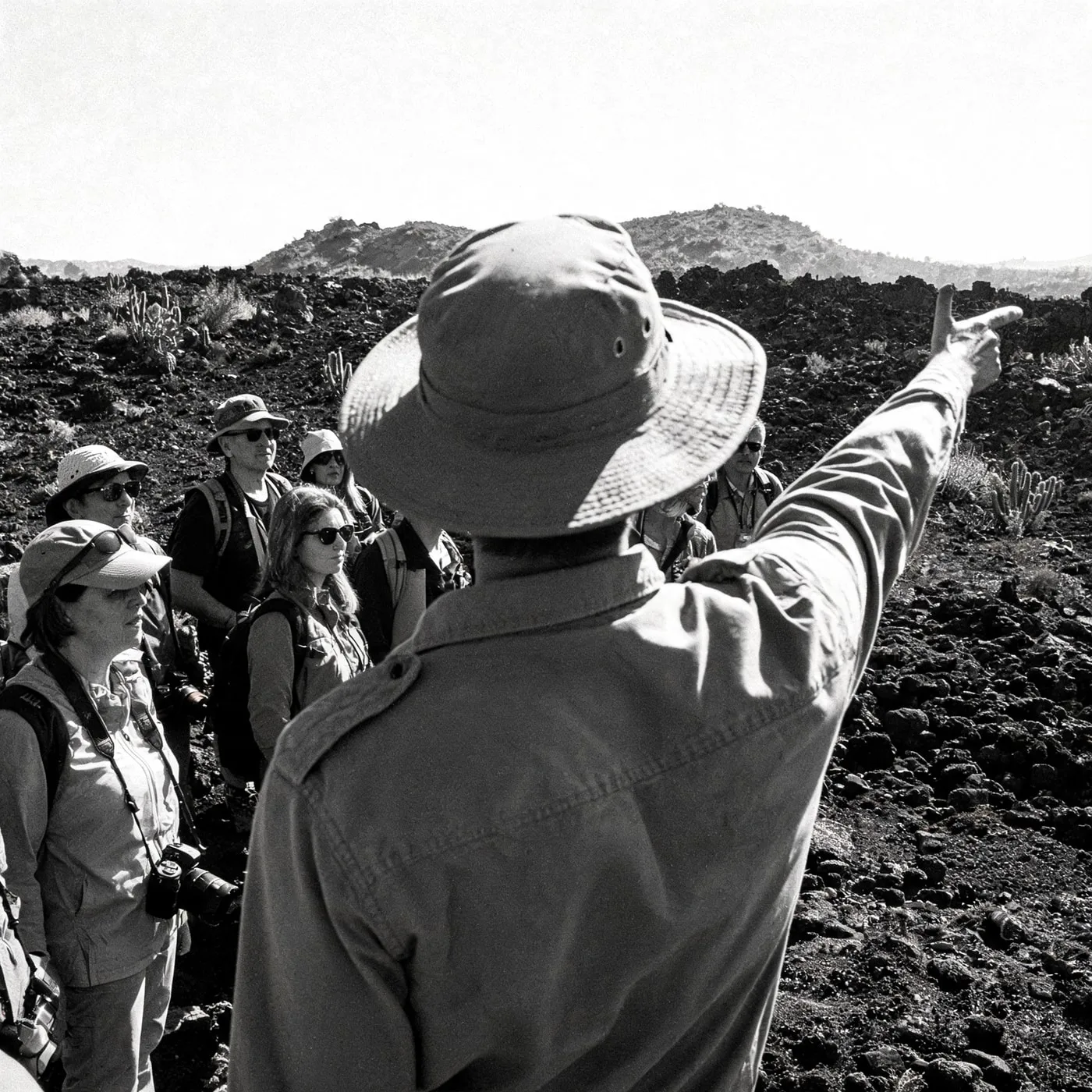 Guide pointing out a landmark to guests across the lava field, Punta Pitt, Galápagos